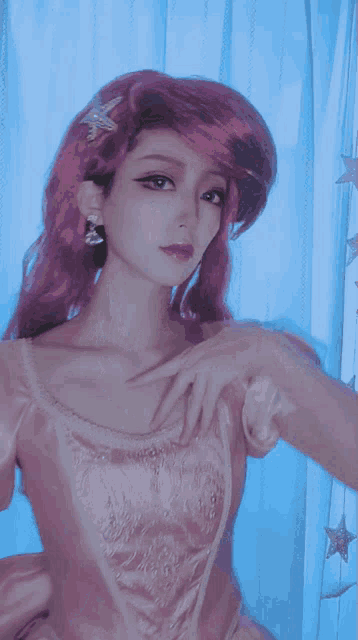 a woman in a pink dress with a star in her hair is standing in front of a blue curtain