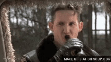 a man in a leather jacket and gloves is blowing a whistle while sitting in a car .