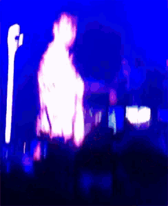 a man in a colorful shirt stands in front of a microphone on a stage