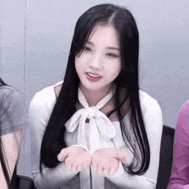 a woman with long black hair is wearing a white shirt with a bow tie