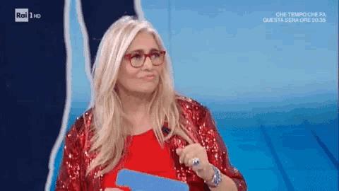 a woman wearing glasses and a red sequined jacket is talking on a tv show .