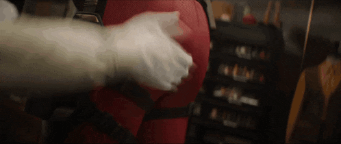 a person wearing a white glove is holding a red object in their hands .