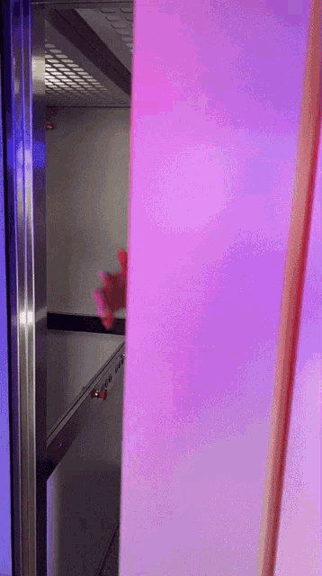 a person 's hand is visible behind a purple and blue wall