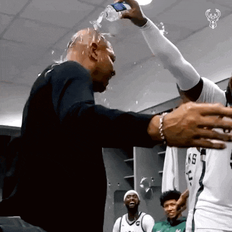 a man is pouring water on another man 's head .