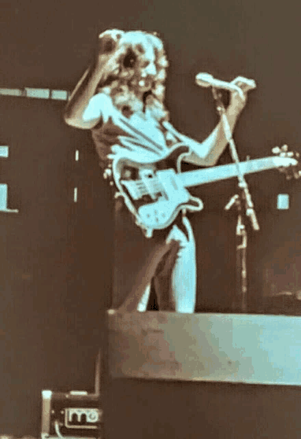 a man playing a guitar and singing into a microphone