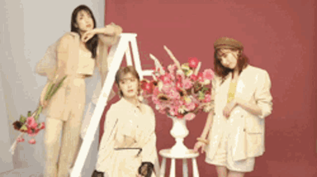 three women standing next to a vase of flowers