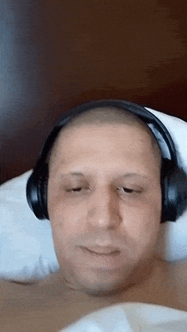 a man wearing headphones is laying on a bed .