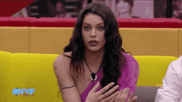 a woman sitting on a yellow couch with #gfvip written on the bottom right