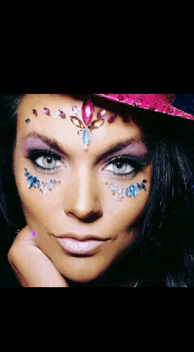a woman with rhinestones on her face is wearing a pink top hat