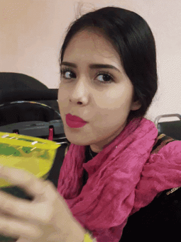 a woman in a pink scarf is holding a yellow bag