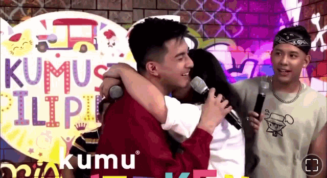 a man and a woman hugging in front of a sign that says kumus filipi