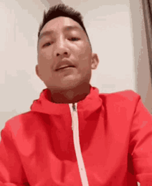 a man wearing a red jacket is looking at the camera .