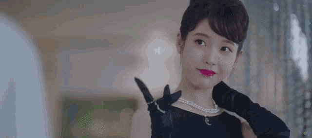 a woman in a black dress and black gloves is smiling and looking up .