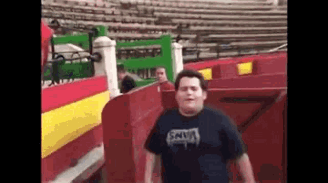 a man in a black shirt is walking through a bullring .