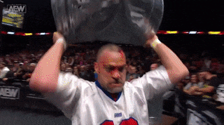 a man wearing a jersey that says aew on it holds a large object over his head