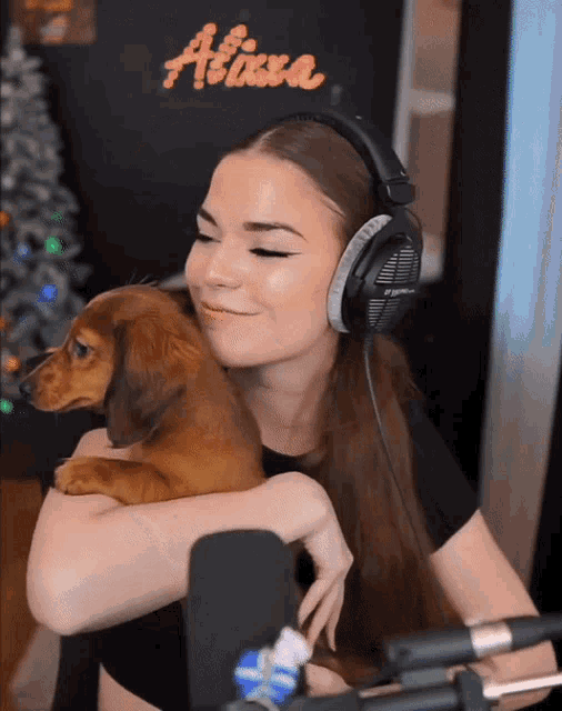 a woman wearing headphones holds a brown dog in her arms