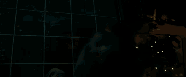 a man in a black hoodie is standing in front of a window in a dark room