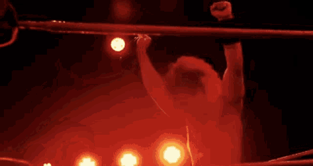 a man is standing in a wrestling ring with his arm in the air .