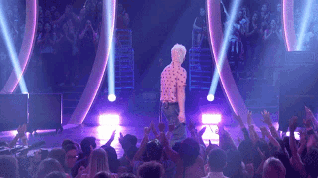 a man stands on a stage in front of a crowd and a sign that says rode on it