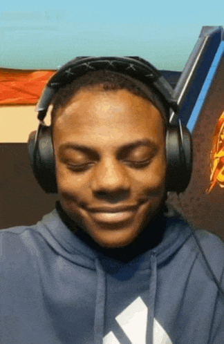 a man wearing headphones and a blue hoodie is smiling .