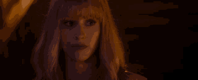 a close up of a woman 's face with long blonde hair and bangs