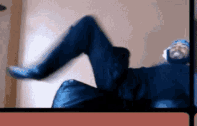 a person in a blue suit is laying on their stomach with their legs up .