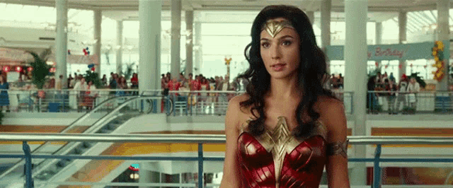 a woman dressed as wonder woman is standing in a mall .