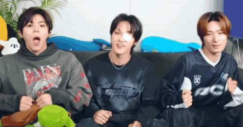three young men are sitting on a couch with one wearing a shirt that says spice