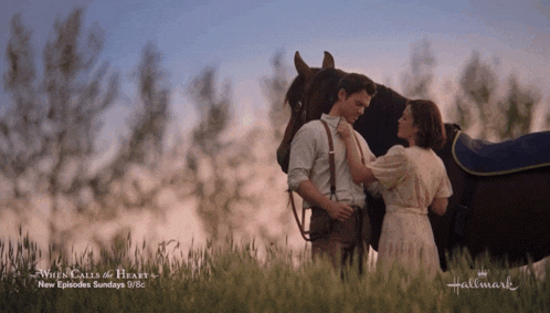 a man and a woman standing next to a horse with a hallmark logo in the background