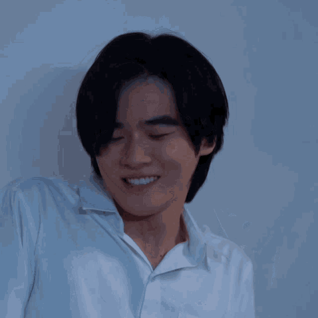 a man in a white shirt is smiling and looking to the side