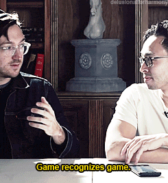 two men are sitting at a table with the words game recognizes game below them