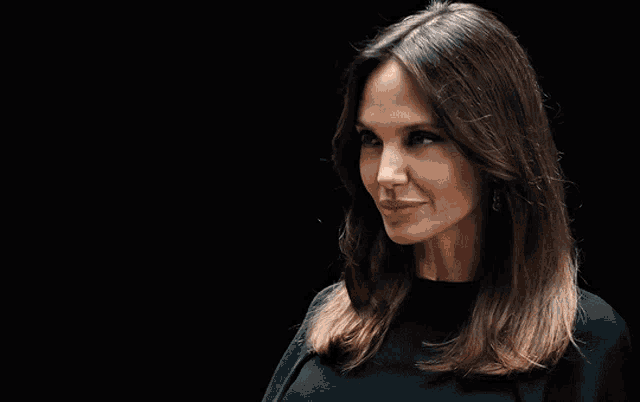 a woman with long brown hair is wearing earrings and a black dress