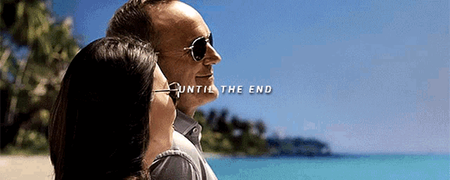a man and a woman are standing on a beach and looking at the ocean .