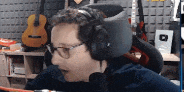 a man wearing headphones and glasses is talking into a microphone .