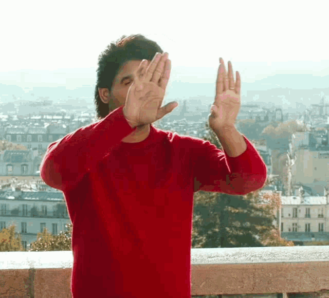 a man in a red sweater is covering his face with his hands