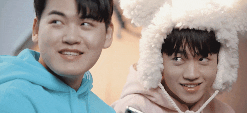 a boy wearing a bunny hat is standing next to another boy