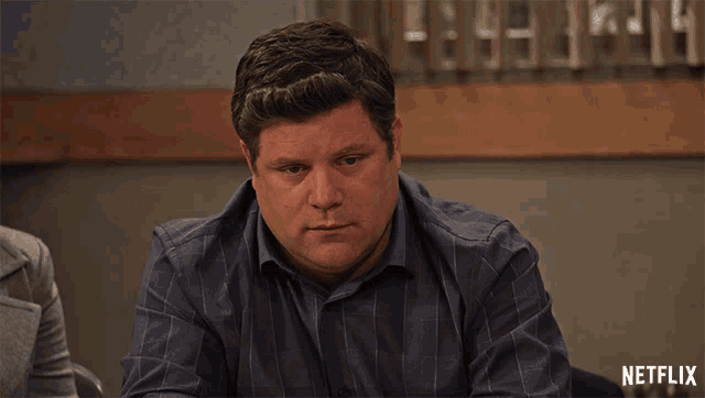 a man sits at a table with a netflix logo on the bottom right