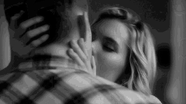 a man and a woman are kissing in a black and white photo .