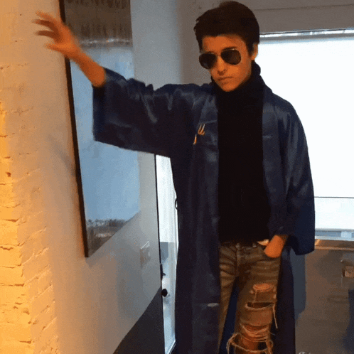 a person wearing sunglasses and a blue robe has the letter m on their jacket
