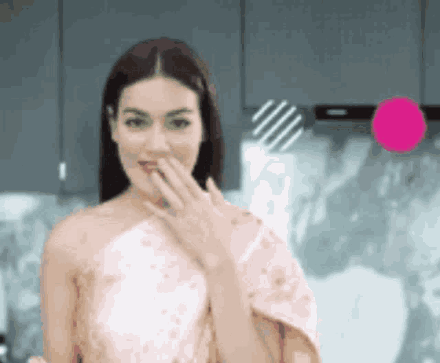 a woman in a pink dress is covering her mouth with her hand