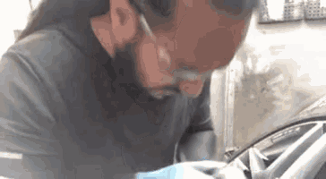 a man with a beard is working on a car tire .