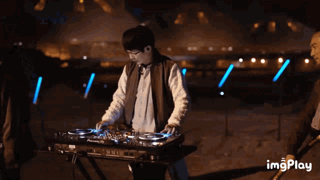 a man playing a pioneer dj mixer at night