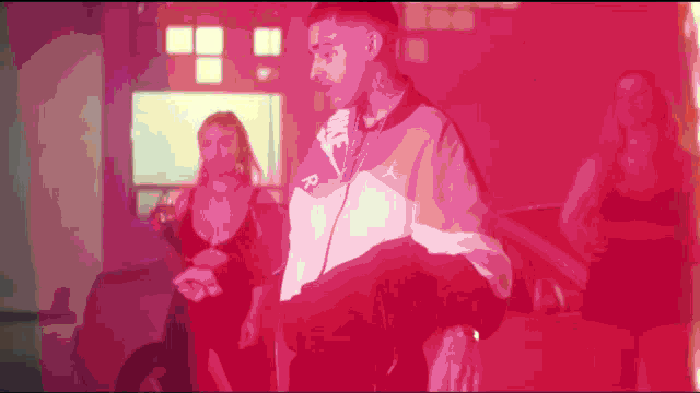 a man with a tattoo on his face is standing in a room with two women