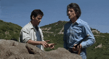 two men standing next to each other one holding a gun