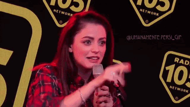 a woman in a plaid shirt is holding a microphone and saying non dire niente