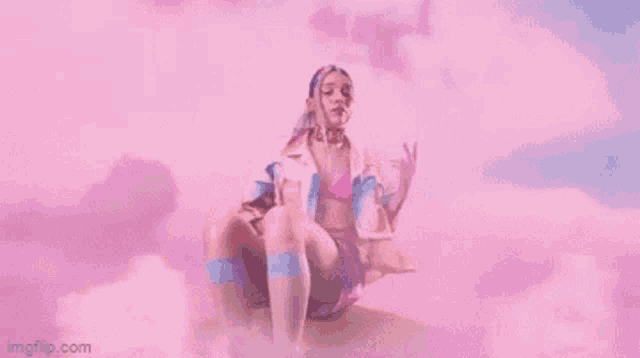 a woman is sitting on a cloud in a pink sky .