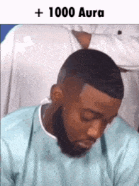 a man with a beard is sitting down with his eyes closed and a caption that says + 1000 aura .