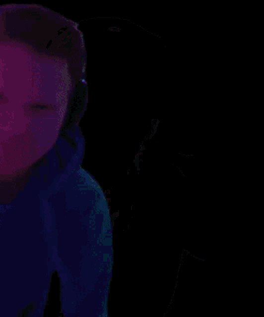 a man wearing headphones and a green hoodie is giving the middle finger