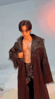 a man without a shirt is wearing a fur coat .