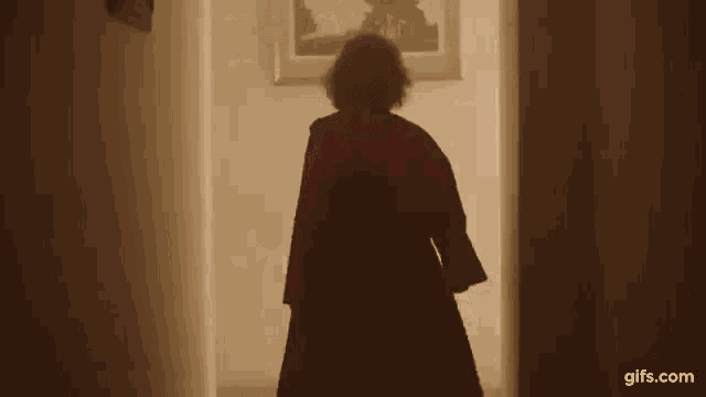 a woman in a red coat is walking through a hallway .